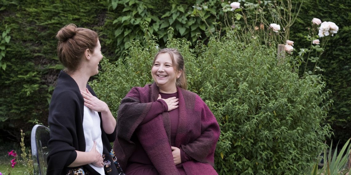 A woman and a therapist talking in a garden.