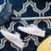 cleaning a dark blue carpet with a vacuum which is next to a pair of white shoes