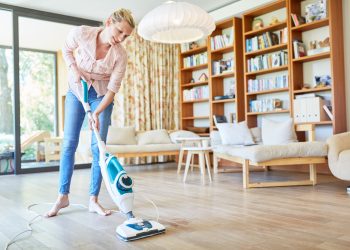 A woman is vacuuming the wooden floor of the study room