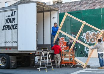 4 men putting furniture into a moving truck