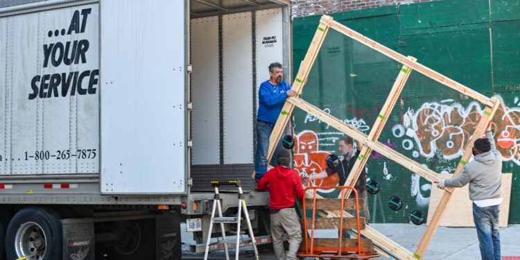 4 men putting furniture into a moving truck