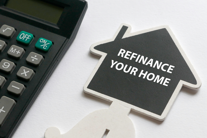 Selective focus of calculator and wooden house shape board written with Refinance Your Home on a white background