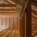 The Importance of Properly Insulating Your Attic Banner Image - Construction Worker Looking Downstairs. Attic Wooden Roof Construction. House Cover. Wooden Structure