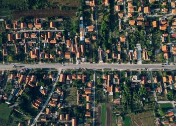 A vibrant aerial view of a residential area, featuring buildings and lush plants amidst the bustling crowd below.