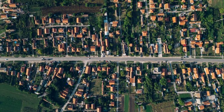 A vibrant aerial view of a residential area, featuring buildings and lush plants amidst the bustling crowd below.
