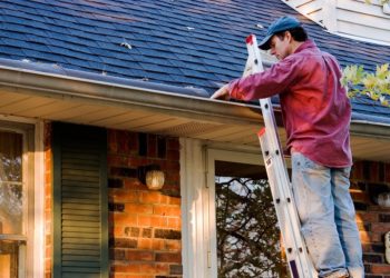 Man Cleaning Gutters on Ladder