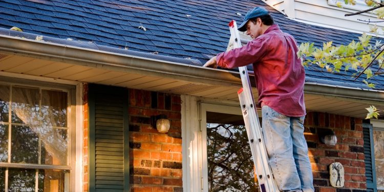 Man Cleaning Gutters on Ladder