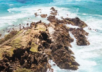 The iconic and famous Byron Bay lighthouse and rocky seascape on a hot autumn day in Byron Bay, New South Wales, Australia.