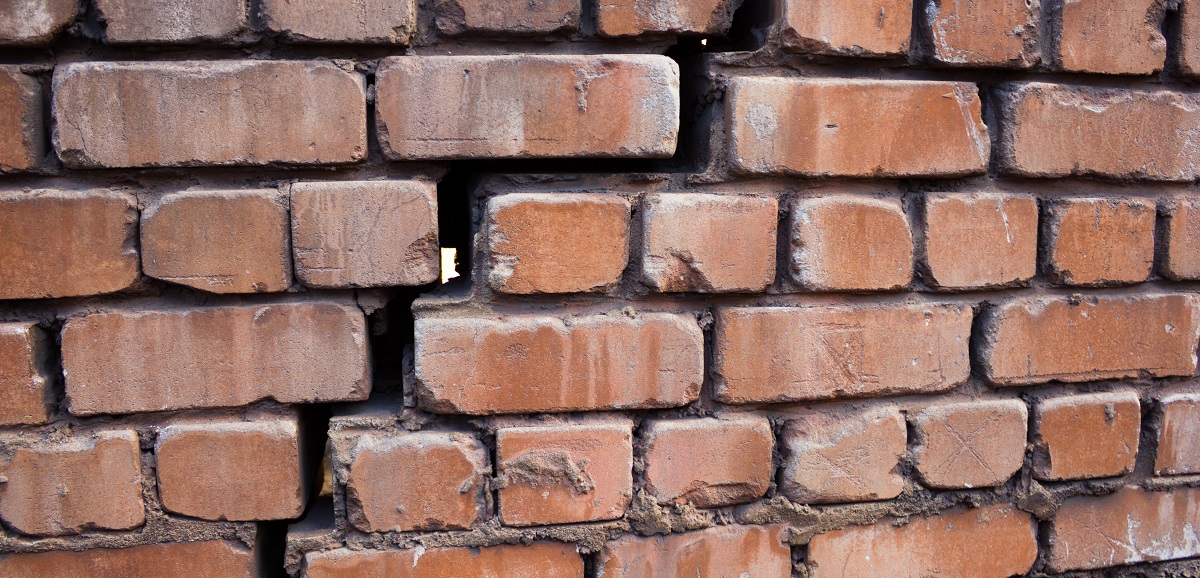 Large and wide crack in the wall of red brick
