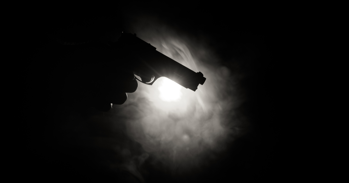 hand holding gun in the dark