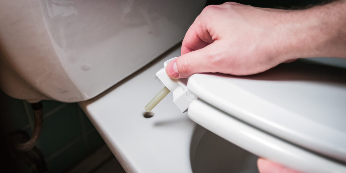 hand installing toilet seat