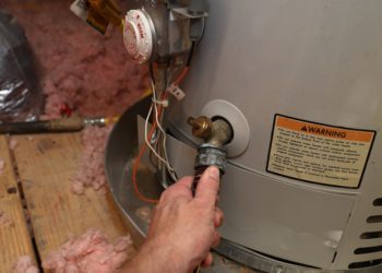 Hand attaches hose to a home water heater to perform maintenance