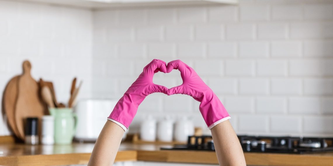 Heart made of pink protective gloves on white kitchen background.. Woman hands wearing protective gloves. Concept of clean kitchen, successful thumb up yes ok sign