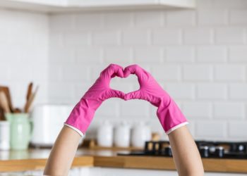 Heart made of pink protective gloves on white kitchen background.. Woman hands wearing protective gloves. Concept of clean kitchen, successful thumb up yes ok sign