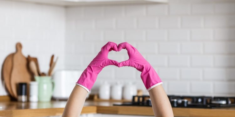 Heart made of pink protective gloves on white kitchen background.. Woman hands wearing protective gloves. Concept of clean kitchen, successful thumb up yes ok sign