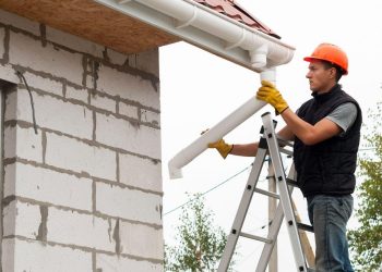 man fixing gutters on a house