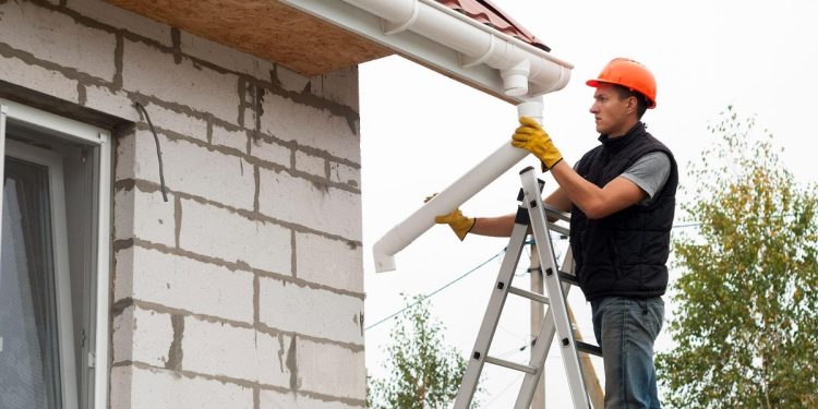 man fixing gutters on a house
