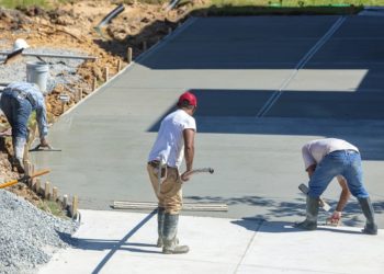Unidentifiable hispanic men working on a new concrete driveway at a residential home