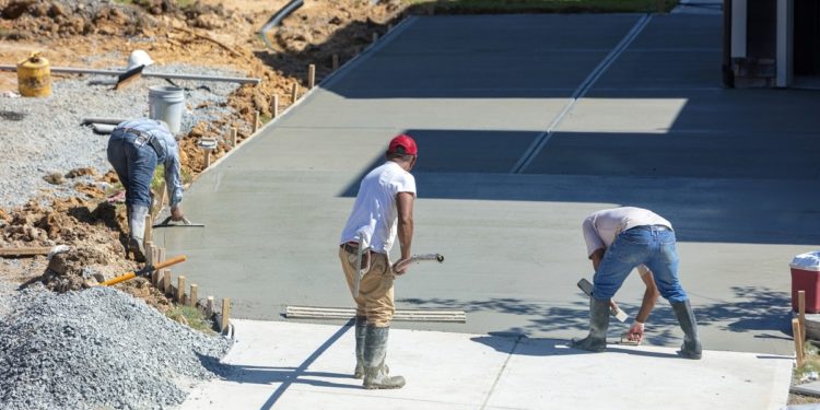 Unidentifiable hispanic men working on a new concrete driveway at a residential home