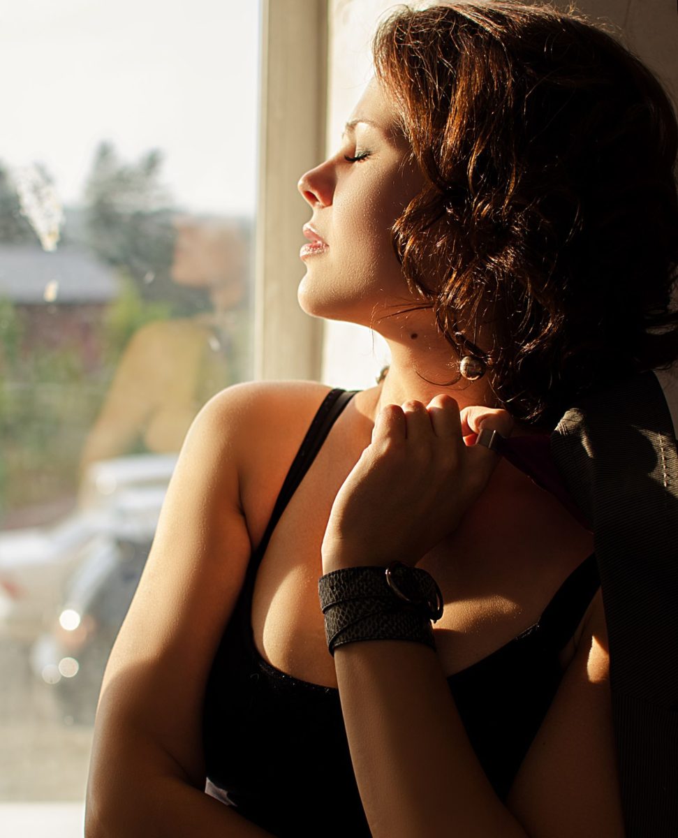 a woman enjoy the natural light beside the window