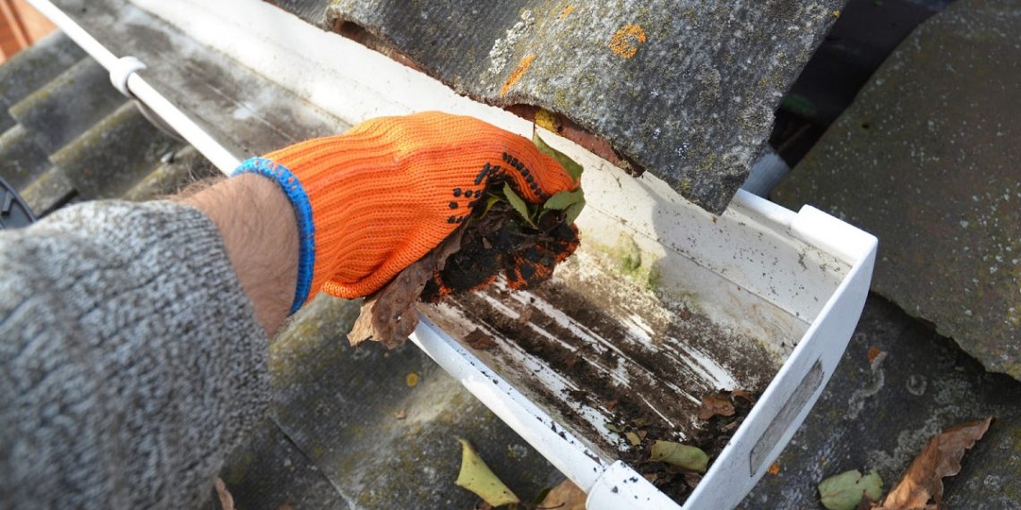 Rain Gutter Cleaning from Leaves in Autumn with hand. Roof Gutter Cleaning Tips. Clean Your Gutters Before They Clean Out Your Wallet. Step by Step. Gutter Cleaning.