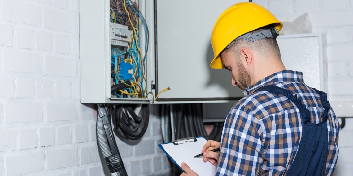 Professional electrician inspecting wires in electrical box