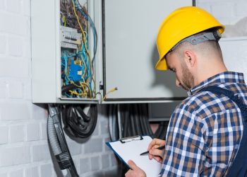 Professional electrician inspecting wires in electrical box