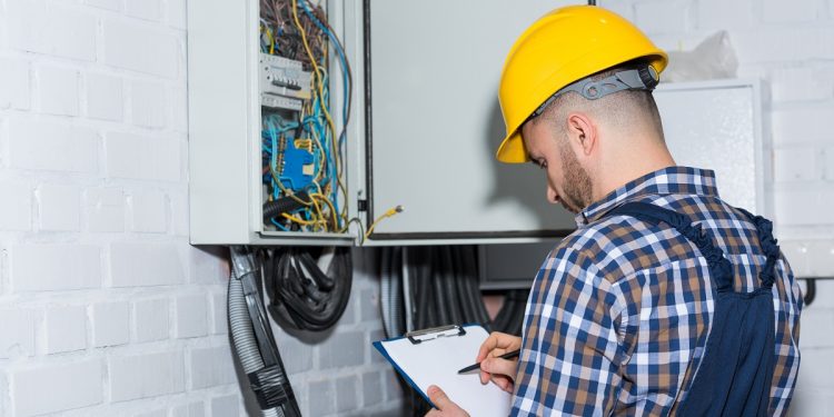 Professional electrician inspecting wires in electrical box