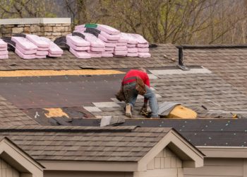 Roofing contractor removing the old tiles before replacing with new shingles on a townhouse roof