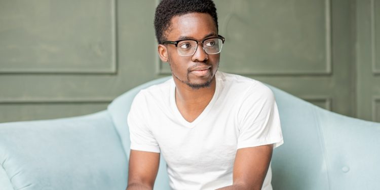 Portrait of a young afro ethnicity man sitting on the couch during the psychological session with psychologist in the office