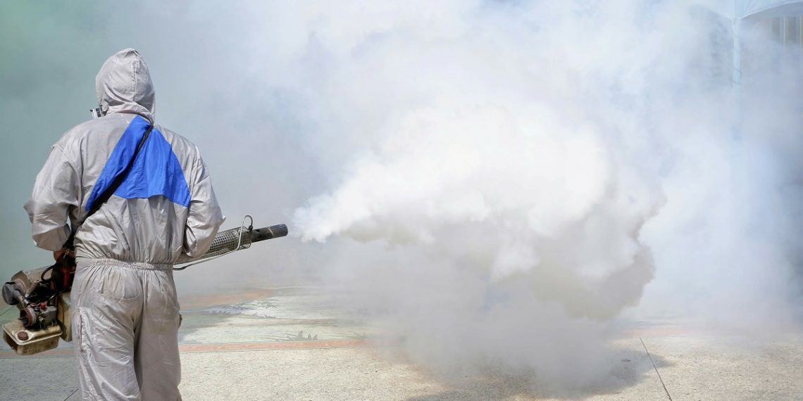 Rear view of health personnal worker using fogging machine spray