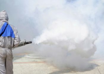 Rear view of health personnal worker using fogging machine spray