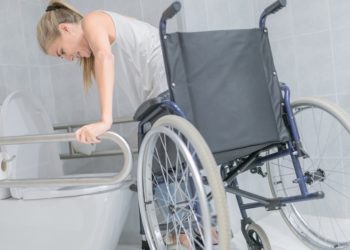 Woman moving from wheelchair to bathroom