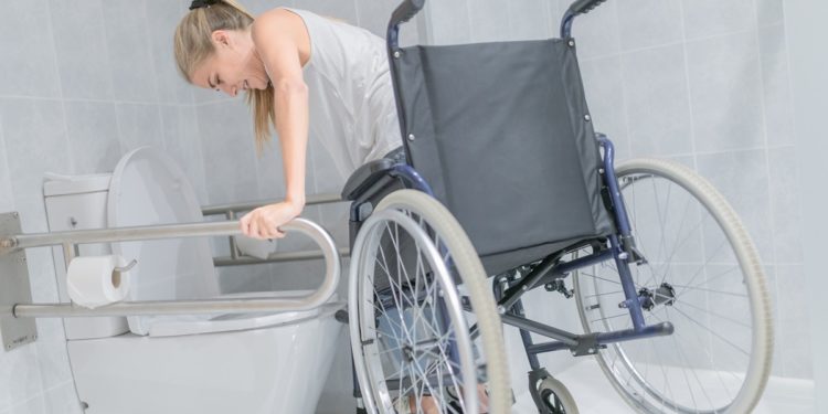 Woman moving from wheelchair to bathroom
