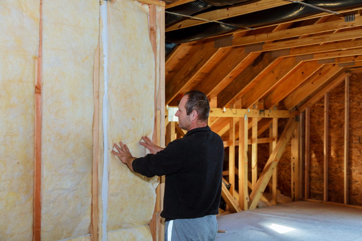 Worker thermally insulating a house attic using mineral wool installation of insulation in the house insulation of the house