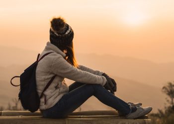 Young woman traveler looking at sunrise over the mountain